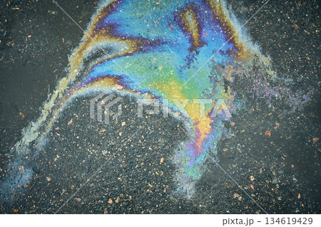 A vibrantly colored oil slick creates an artistic texture on wet asphalt. 134619429