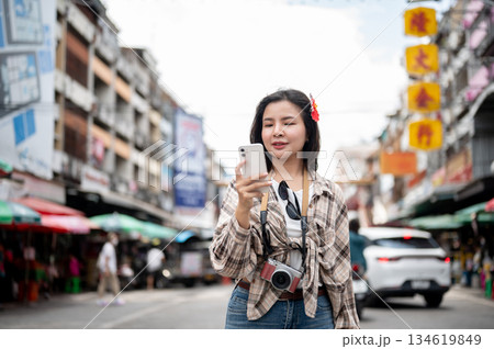 Asian tourist woman looking at phone checking direction while standing by the road in a local market 134619849