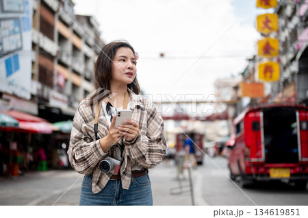 Asian tourist woman looking nervous as holding phone with both hands standing by the road in market 134619851