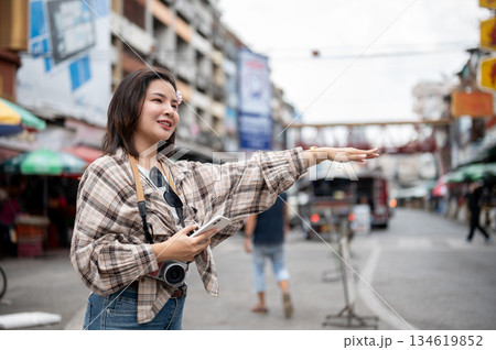 Asian tourist woman holding phone and raising an arm to catch taxi as standing by the road in market 134619852