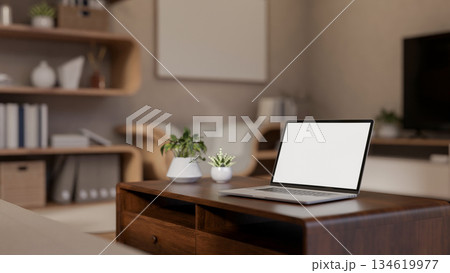 Blank screen laptop with potted plants aside on wooden table in a living room with stylish furniture 134619977