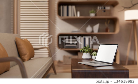 Blank screen laptop with potted plants aside on table in a cosy living room with wooden furniture. Blank screen laptop with potted plants aside on table in a cosy living room with wooden furniture. 134619982