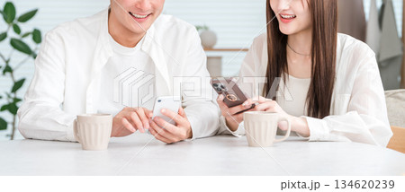 ダイニングテーブルでホットドリンクを飲みながら会話するカップル,夫婦 ダイニングテーブルでホットドリンクを飲みながら会話するカップル,夫婦 134620239