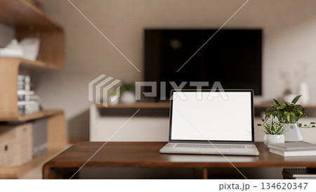 Blank screen laptop and books with potted plants aside on wooden table in a living room or bedroom. Blank screen laptop and books with potted plants aside on wooden table in a living room or bedroom. 134620347