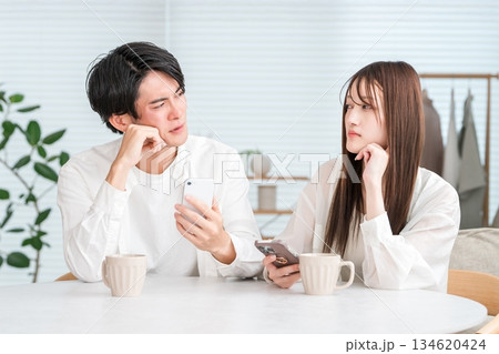 ダイニングテーブルでホットドリンクを飲みながら会話するカップル,夫婦 134620424