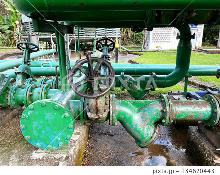 Green industrial valves and pipelines at a geothermal power plant, representing underground heat extraction, pressure control systems, and renewable energy infrastructure for sustainable electricity Green industrial valves and pipelines at a geothermal power plant, representing underground heat extraction, pressure control systems, and renewable energy infrastructure for sustainable electricity 134620443