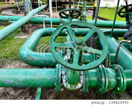 Green industrial valves and pipelines at a geothermal power plant, representing underground heat extraction, pressure control systems, and renewable energy infrastructure for sustainable electricity 134620445