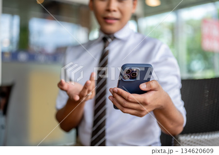 Male office worker holding phone talking on speaker explaining on video call in cafe or coffee shop 134620609