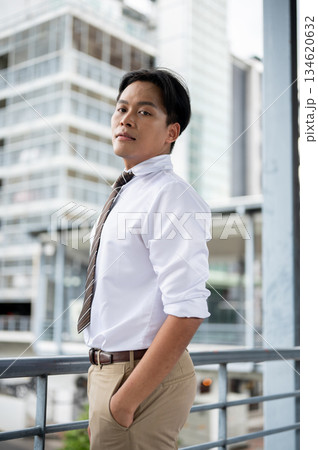 Businessman or office worker standing looking sideway with hand in pocket on a pedestrian footbridge 134620632