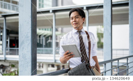 Businessman or office worker holding tablet other hand in pocket standing on pedestrian footbridge. 134620649