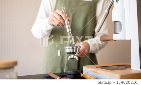 Close up of barista using brush cleaning used coffee ground in machine container at cafe counter bar 134620810
