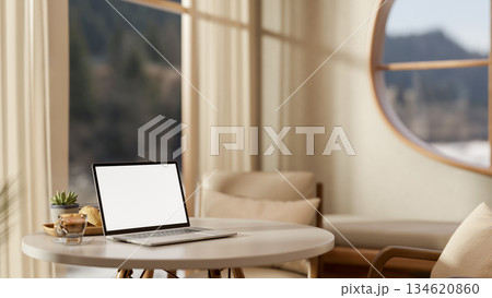 White screen laptop and coffee on round wooden table and chairs with blurred living room background. White screen laptop and coffee on round wooden table and chairs with blurred living room background. 134620860