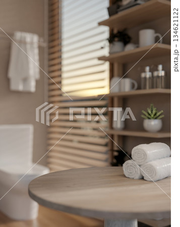 Towels on a round wooden table and display shelf with blurred background of modern toilet or bathroom 134621122