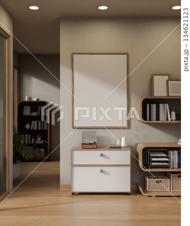 A vinyl player on wooden drawer cabinet under blank frame on wall next to a stylish bookshelf in a modern living room. 134621123