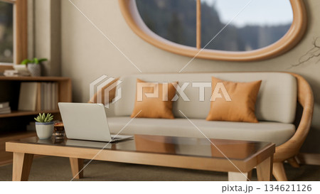 Laptop and coffee on glass top wooden table and sofa under oval shape window in modern living room. Laptop and coffee on glass top wooden table and sofa under oval shape window in modern living room. 134621126