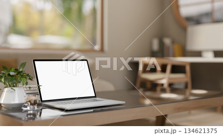 White screen laptop with books and coffee cup on glass top wooden table in a bedroom or living room. 134621375