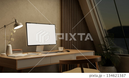 White screen computer with books aside lamp on wooden table and armchair in a bedroom or living room 134621387