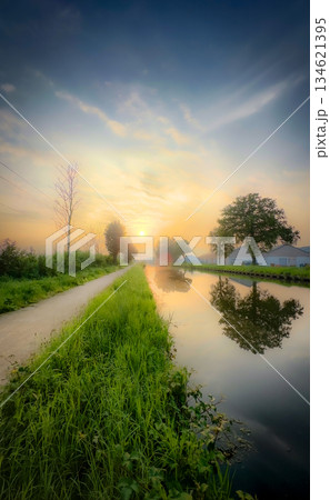A Serene Sunset Over the Picturesque Canal with Beautiful Reflections and Lush Greenery 134621395