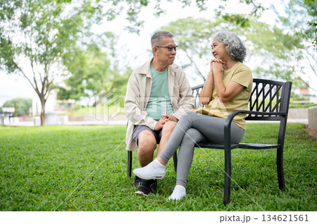 Glasses old man looking lovingly at a clasping hands woman while sitting together on bench in park 134621561