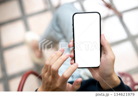 Close up of hand holding touching blank screen smartphone using application or social media on bench Close up of hand holding touching blank screen smartphone using application or social media on bench 134621979
