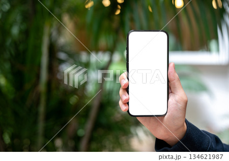 Close up of a man's hand holding and showing a blank screen smartphone while being outdoors. Close up of a man's hand holding and showing a blank screen smartphone while being outdoors. 134621987