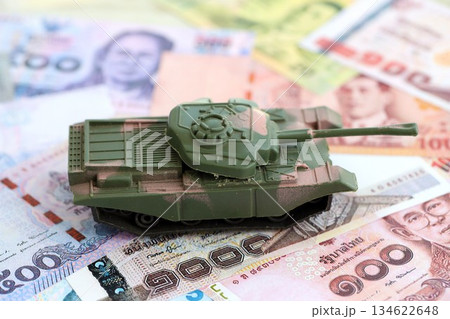 Thai baht currency money bills and toy tank close up. The concept of army funds and weapons sales Thai baht currency money bills and toy tank close up. The concept of army funds and weapons sales 134622648