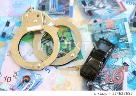 Kuwaiti dinar currency money bills and toy car with handcuffs close up. The concept of car accident Kuwaiti dinar currency money bills and toy car with handcuffs close up. The concept of car accident 134622653