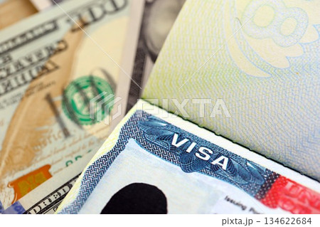 Fee for US visa 250 dollars, USA Visa in passport and USD money bills in background close up Fee for US visa 250 dollars, USA Visa in passport and USD money bills in background close up 134622684