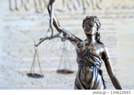 The statue of justice Themis or Justitia, the blindfolded goddess of justice against US Constitution page. Judgement and punishment in United States The statue of justice Themis or Justitia, the blindfolded goddess of justice against US Constitution page. Judgement and punishment in United States 134622693