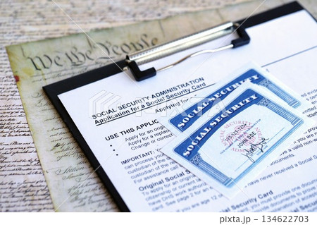 United States social security number cards lies on Application from social security administration on US Constitution page close up United States social security number cards lies on Application from social security administration on US Constitution page close up 134622703