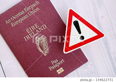 Ireland passport with exclamation sign on white wooden background close up. Problems with citizenship in Europe concept Ireland passport with exclamation sign on white wooden background close up. Problems with citizenship in Europe concept 134622731