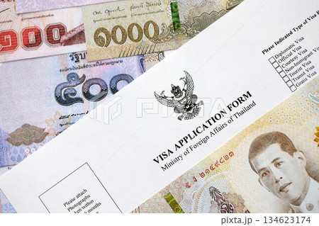 Visa application form to enter Thailand on table with thai money bills close up 134623174