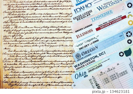 Big amount of driving licenses from different USA states on constitution page. Stack of driving license specimen cards Big amount of driving licenses from different USA states on constitution page. Stack of driving license specimen cards 134623181
