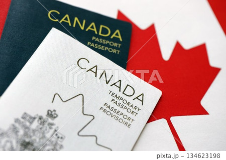 Canadian temporary and permanent passports lies on flag close up 134623198