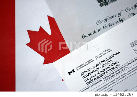 Canadian certificate of citizenship and application on Canadian flag close up Canadian certificate of citizenship and application on Canadian flag close up 134623267