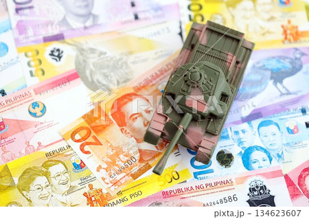 Philippines peso currency money bills and toy tank close up. The concept of army funds and weapons sales 134623607