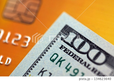 One hundred US dollar bill banknote on gold credit card for banking and payments. Concept of business and bank service One hundred US dollar bill banknote on gold credit card for banking and payments. Concept of business and bank service 134623640