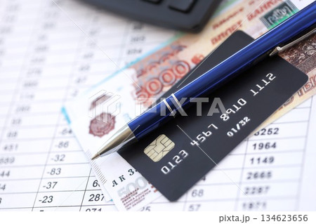 Credit card and pen with russian ruble currency money bills banknotes on calculations document background. Business, financial operations and accounting in Russian Federation 134623656