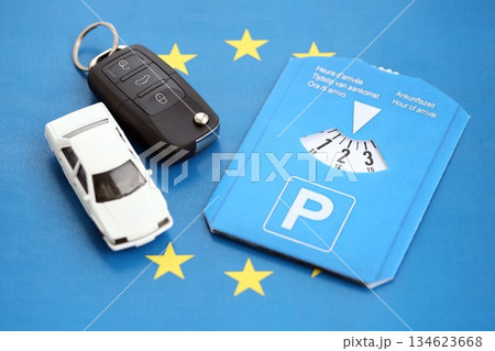 Parking disc for windshield and white toy car with ignition keys on European Union flag. Limited time parking system in european countries. Concept of parking time count in busy parking lots Parking disc for windshield and white toy car with ignition keys on European Union flag. Limited time parking system in european countries. Concept of parking time count in busy parking lots 134623668