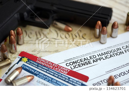 USA firearms license and handgun with bullets on US Constitution. Gun permit and Constitution second amendment concept USA firearms license and handgun with bullets on US Constitution. Gun permit and Constitution second amendment concept 134623701