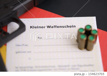 German light firearms license and handgun with bullets on Germany flag close up. Gun permit for light weapon carrying in Deutschland 134623703