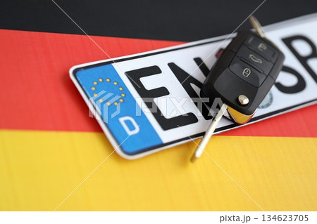 Germany Deutschland car license plate and key on german flag close up. Driving permit and registration concept Germany Deutschland car license plate and key on german flag close up. Driving permit and registration concept 134623705