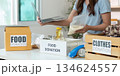 Food Donation. Woman multitasking with laptop while organizing food for charity. 134624557
