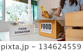 Food Donation. Woman organizing food items for charity in a bright indoor space. 134624559