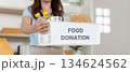 Food Donation. Woman carrying a box of food donations with a smile. 134624562
