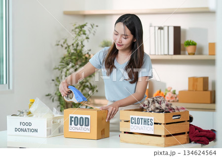 Clothes and Food Donation. Young woman packing items for charity. 134624564