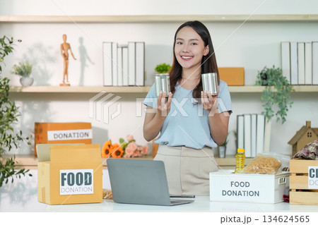 Food Donation. Young woman holding canned goods and smiling. 134624565