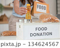 Food Donation. Woman placing a bottle into a donation box. 134624567