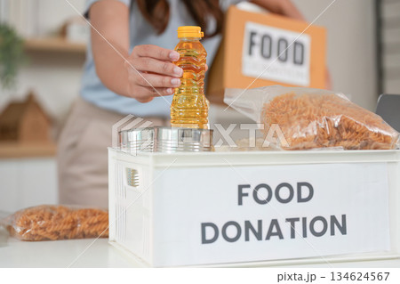 Food Donation. Woman placing a bottle into a donation box. 134624567
