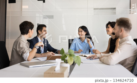 Happy diverse teammates talking seated at conference table Happy diverse teammates talking seated at conference table 134624710